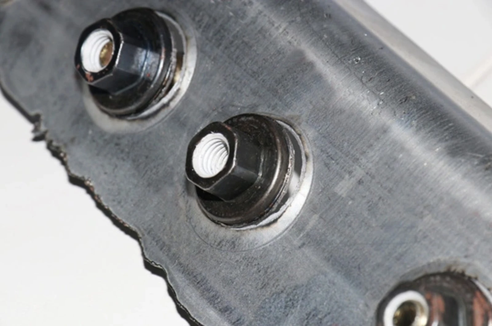 Weld nuts on a steel bracket with clean, undeformed threads.