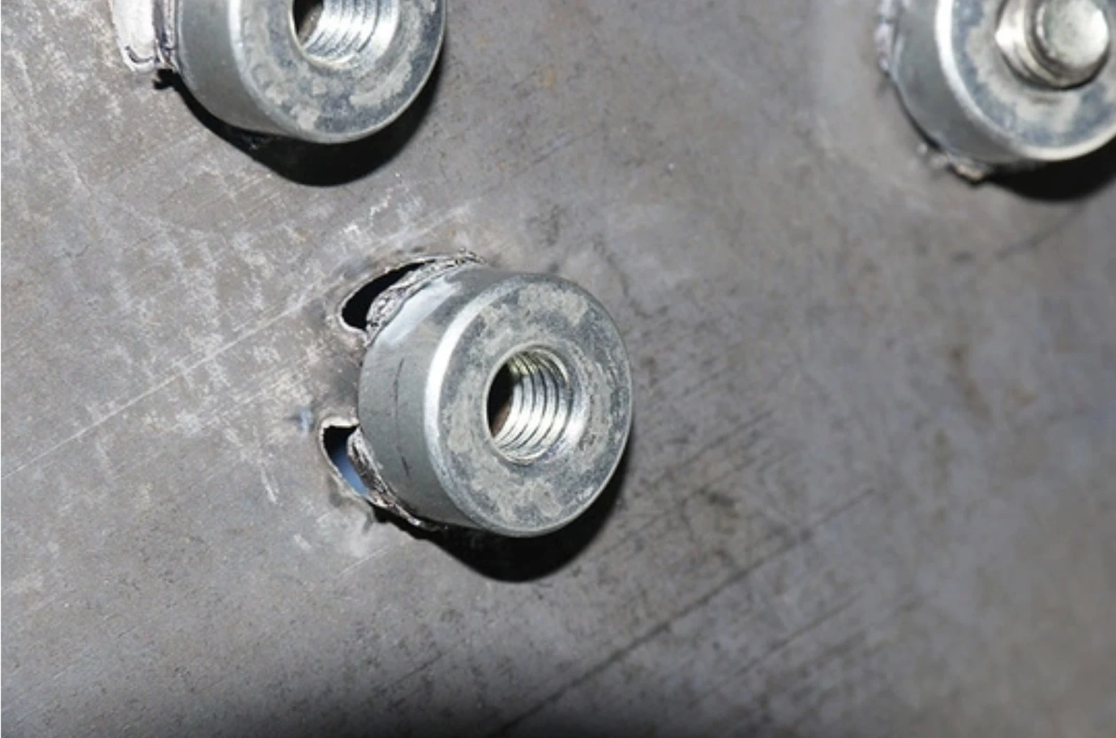 Close-up of a weld nut with a small surrounding heat-affected zone.