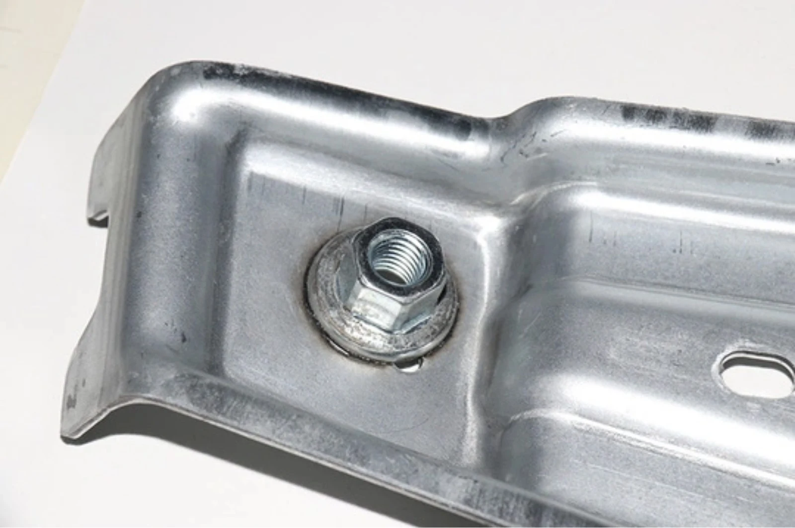 Weld nut on a galvanized bracket with the coating intact around the joint.